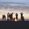 A group of friends hanging out on the beach at sunset	