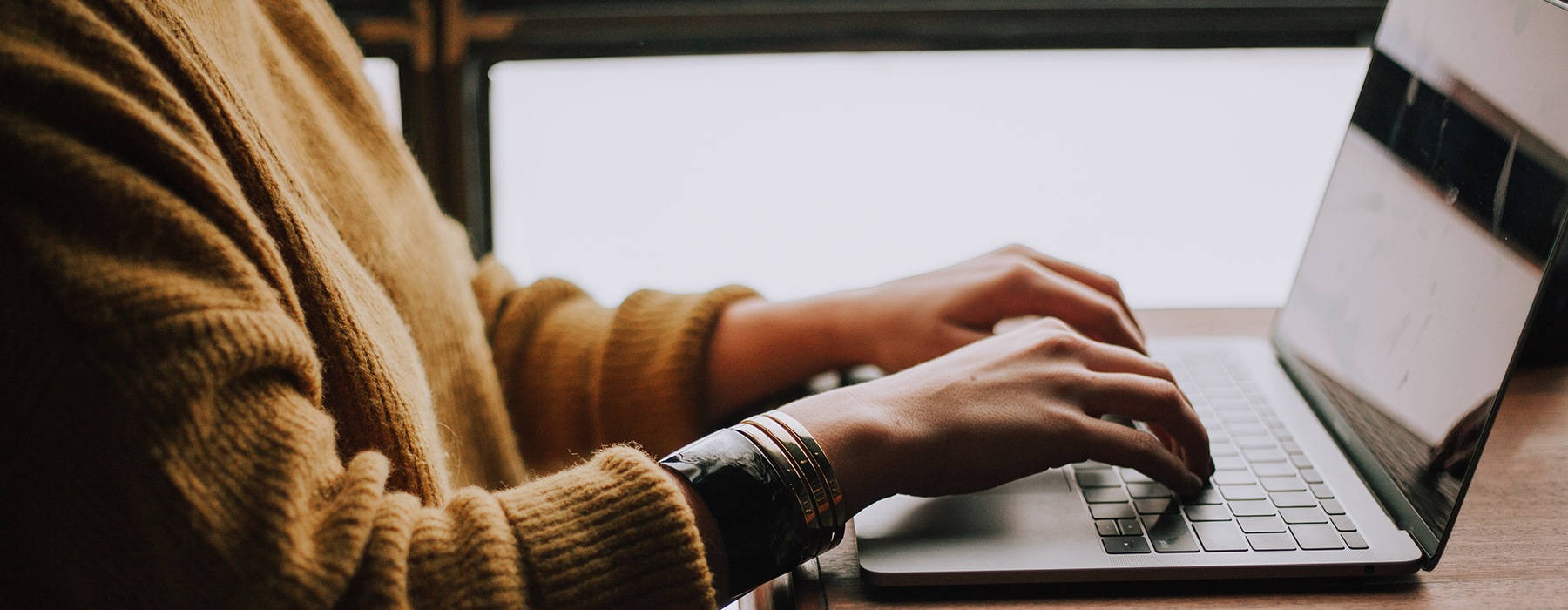 A women sitting at her laptop working near a window 